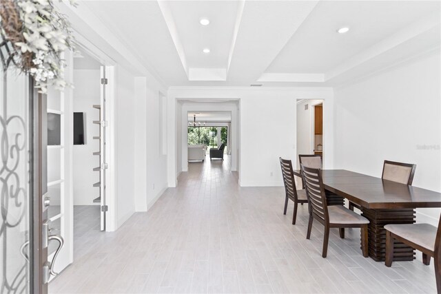 dining room with a tray ceiling and light hardwood / wood-style floors