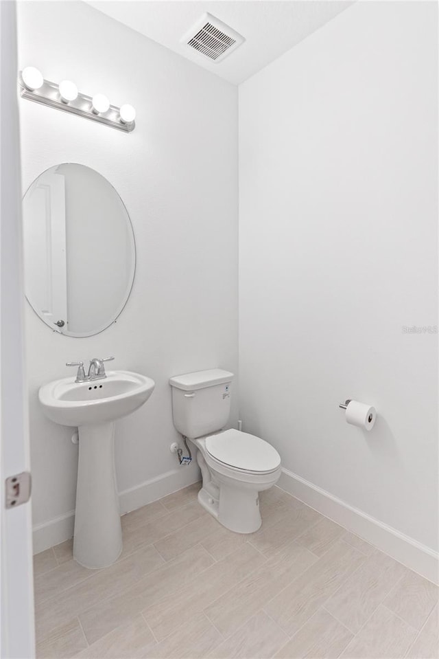 bathroom featuring baseboards, visible vents, toilet, and wood finished floors