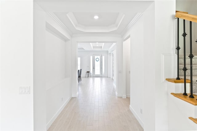 corridor featuring a raised ceiling, crown molding, and light hardwood / wood-style flooring