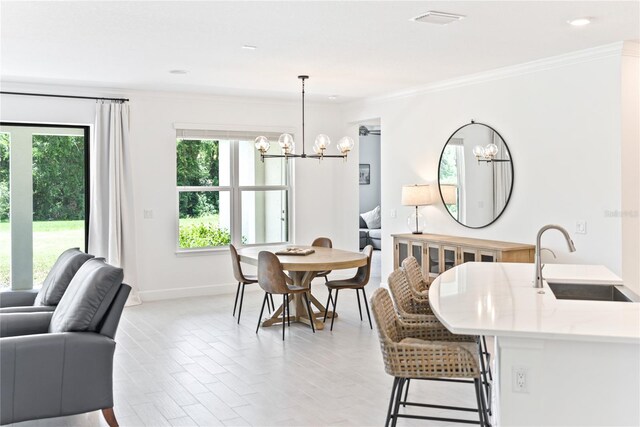 dining space featuring an inviting chandelier, crown molding, and sink