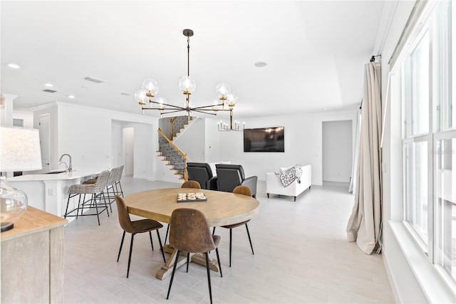 dining area featuring ornamental molding, sink, and an inviting chandelier