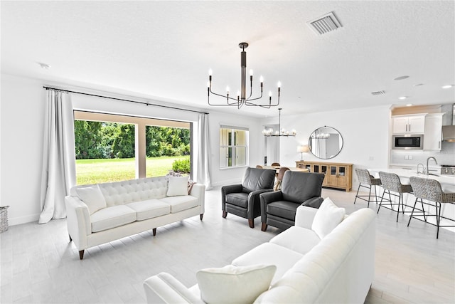 living room featuring a chandelier, a textured ceiling, and light hardwood / wood-style floors