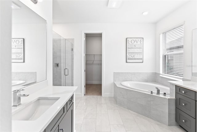 full bath featuring vanity, baseboards, a shower stall, a bath, and a walk in closet