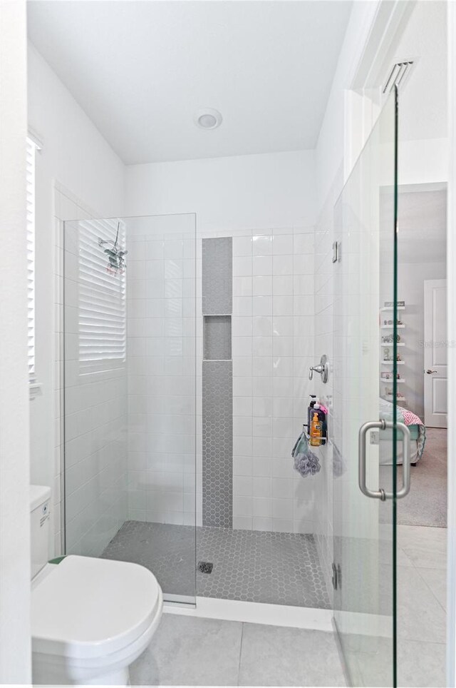 bathroom with tile patterned floors, toilet, and a shower with door