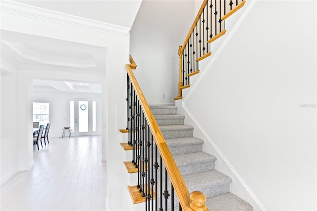 staircase with crown molding and wood finished floors