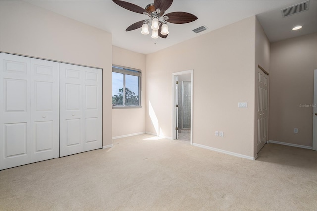 unfurnished bedroom featuring light carpet, a closet, ensuite bath, and ceiling fan