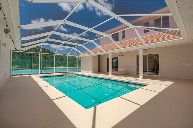 view of swimming pool featuring a patio area, ceiling fan, and glass enclosure