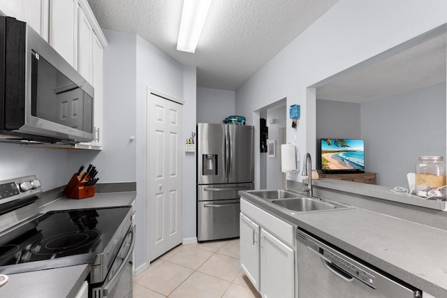 kitchen featuring sink, white cabinetry, a textured ceiling, light tile patterned floors, and appliances with stainless steel finishes