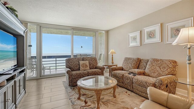 tiled living room with a wall of windows, a healthy amount of sunlight, a water view, and a textured ceiling