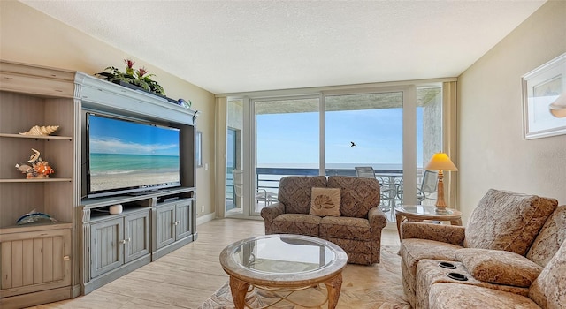 living room featuring a textured ceiling, light wood-type flooring, and floor to ceiling windows