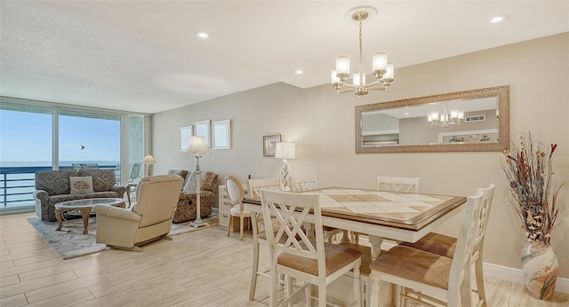 dining area featuring an inviting chandelier, a textured ceiling, plenty of natural light, and a water view