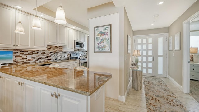 kitchen with hanging light fixtures, white cabinetry, stone counters, and stainless steel appliances