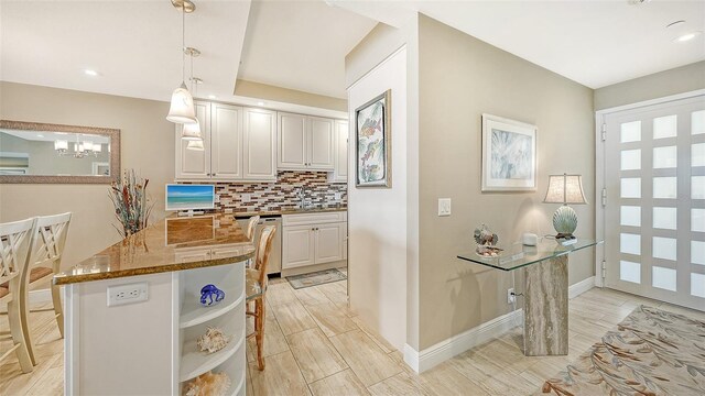 kitchen featuring dark stone countertops, hanging light fixtures, white cabinets, and tasteful backsplash