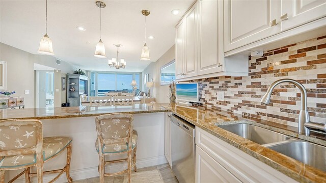 kitchen featuring kitchen peninsula, dishwasher, backsplash, light stone countertops, and sink