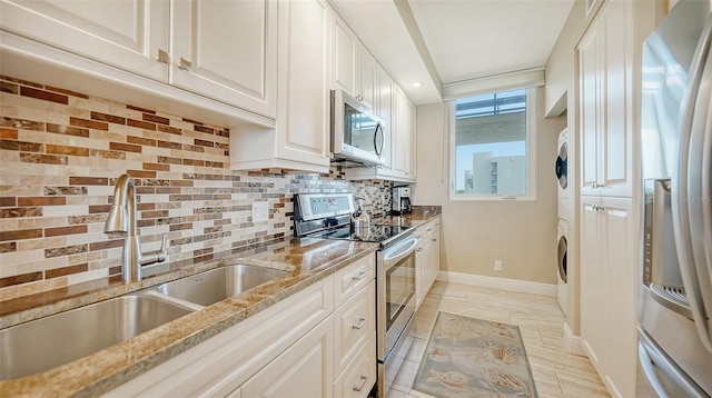 kitchen featuring white cabinetry, stainless steel appliances, light stone counters, and tasteful backsplash