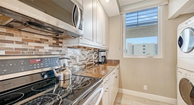 kitchen featuring white cabinetry, stacked washer / dryer, tasteful backsplash, electric stove, and stone countertops