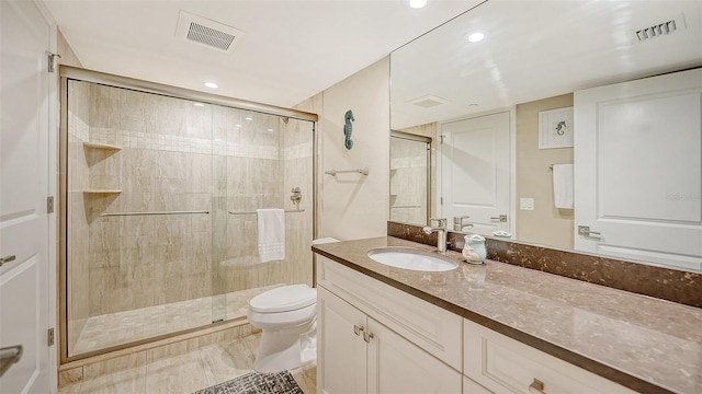 bathroom featuring a shower with shower door, vanity, tile patterned flooring, and toilet