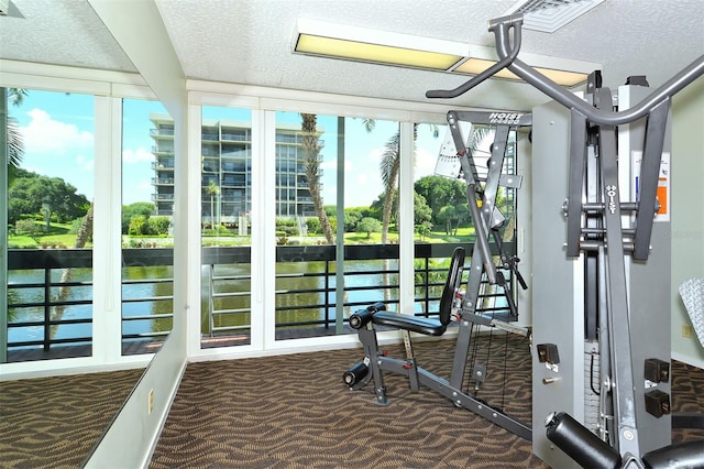 workout area with dark colored carpet and a textured ceiling