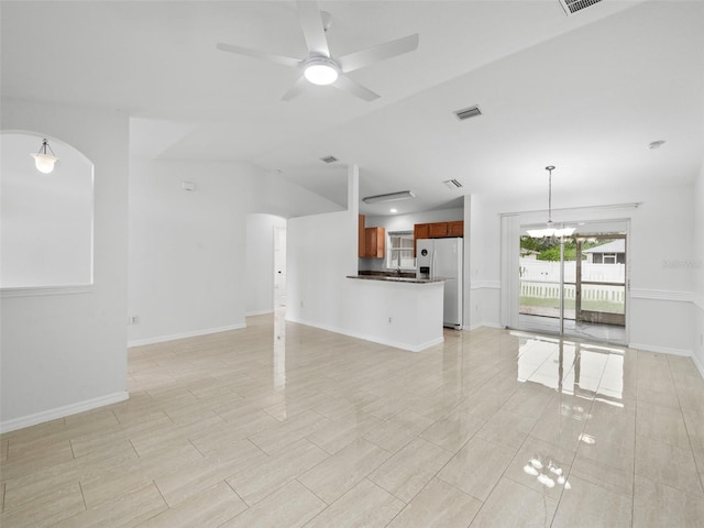 unfurnished living room with sink, ceiling fan with notable chandelier, lofted ceiling, and light tile patterned floors