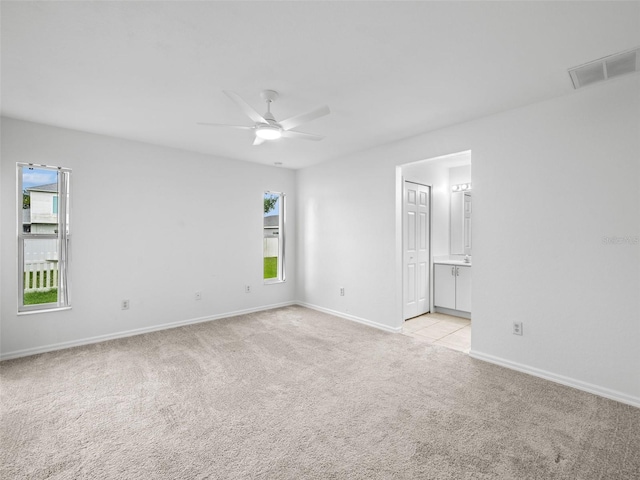 unfurnished bedroom with light carpet, ceiling fan, and connected bathroom