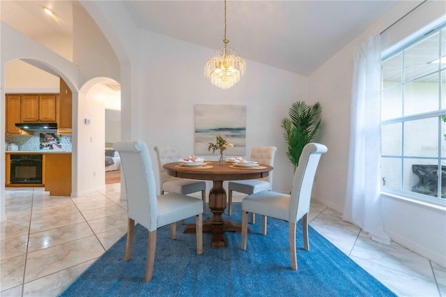 tiled dining space with a chandelier and vaulted ceiling