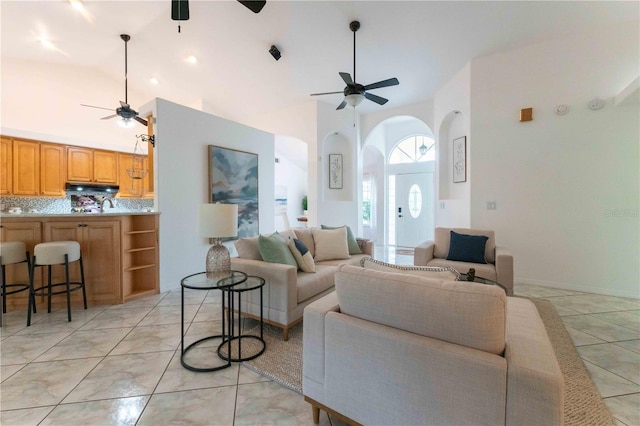 living room with ceiling fan and a towering ceiling