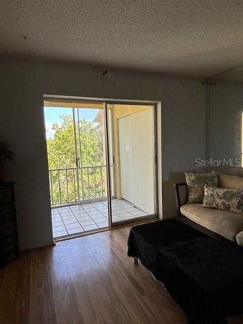 bedroom featuring access to exterior, a textured ceiling, and light hardwood / wood-style flooring