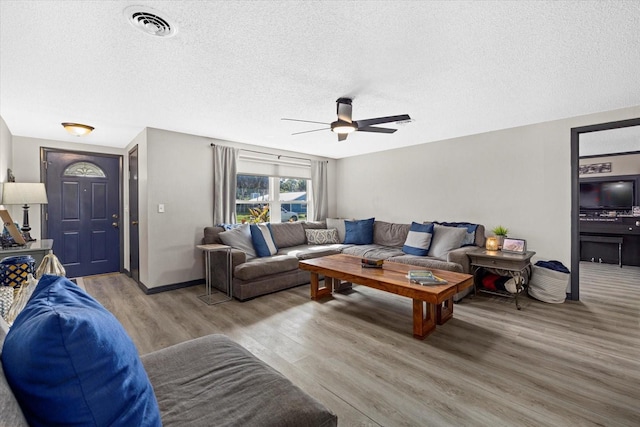 living area with visible vents, ceiling fan, a textured ceiling, wood finished floors, and baseboards