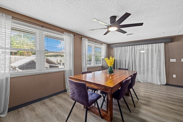 dining space featuring ceiling fan, a textured ceiling, and wood finished floors