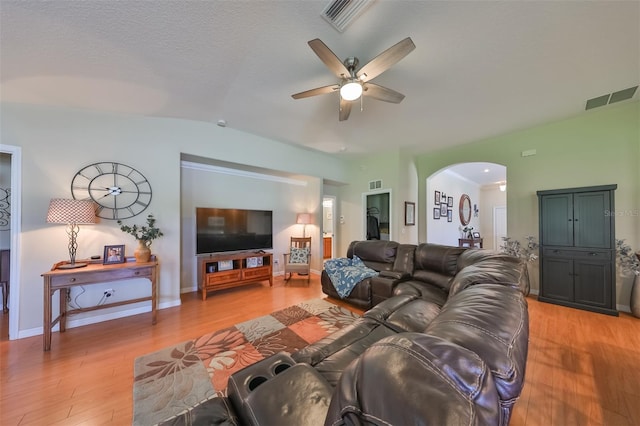 living room with ceiling fan, lofted ceiling, light hardwood / wood-style floors, and a textured ceiling