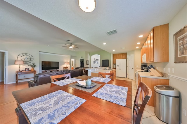 dining room featuring a textured ceiling, ceiling fan, and light wood-type flooring