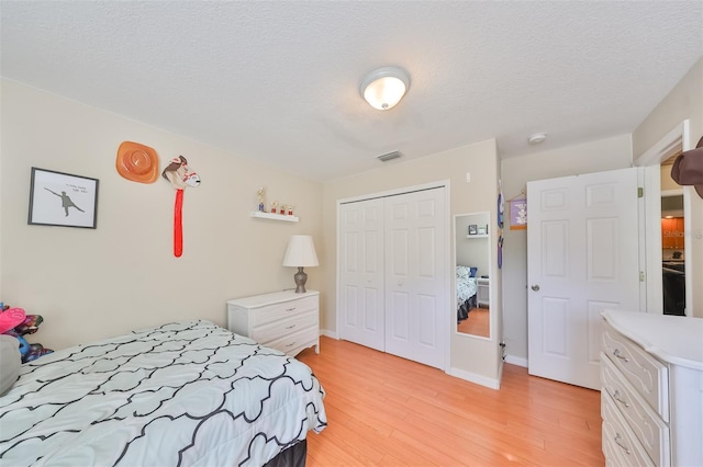 bedroom with a closet, a textured ceiling, and light hardwood / wood-style flooring