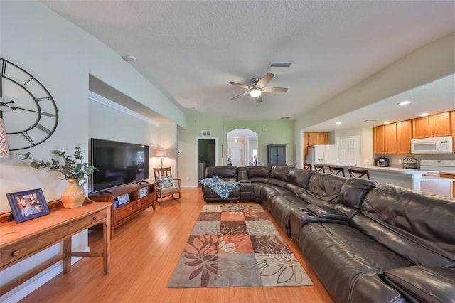 living room with ceiling fan, light hardwood / wood-style floors, and a textured ceiling