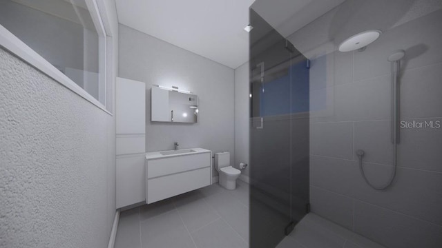 bathroom with vanity, a tile shower, toilet, and tile patterned floors