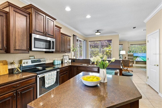 kitchen featuring light tile patterned floors, stainless steel appliances, crown molding, and sink