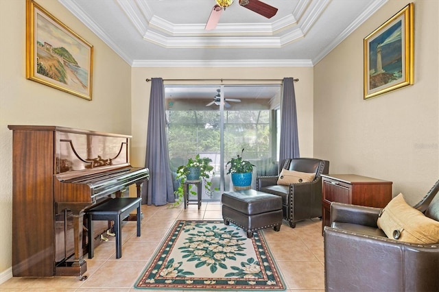 sitting room with light tile patterned flooring, a raised ceiling, ornamental molding, and ceiling fan