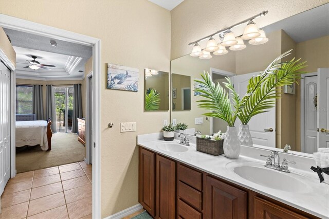 bathroom with double vanity, ceiling fan, a textured ceiling, tile patterned floors, and a tray ceiling