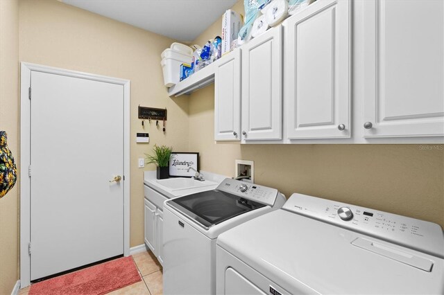 clothes washing area featuring sink, cabinets, light tile patterned floors, and independent washer and dryer