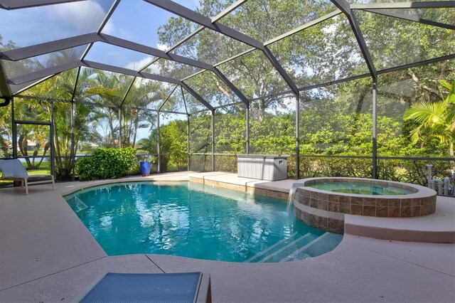 view of pool with a patio area, an in ground hot tub, and glass enclosure