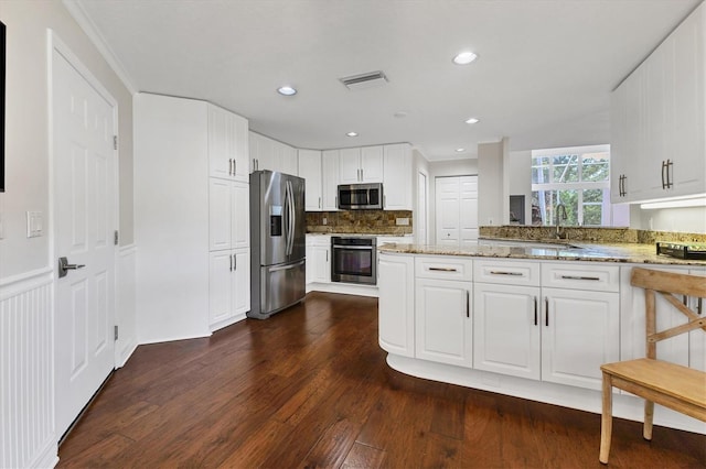 kitchen with light stone countertops, appliances with stainless steel finishes, dark hardwood / wood-style floors, and white cabinets