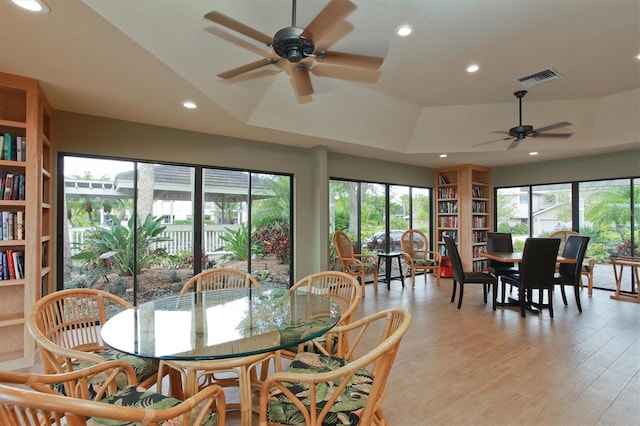 dining area featuring a tray ceiling, ceiling fan, and light wood-type flooring