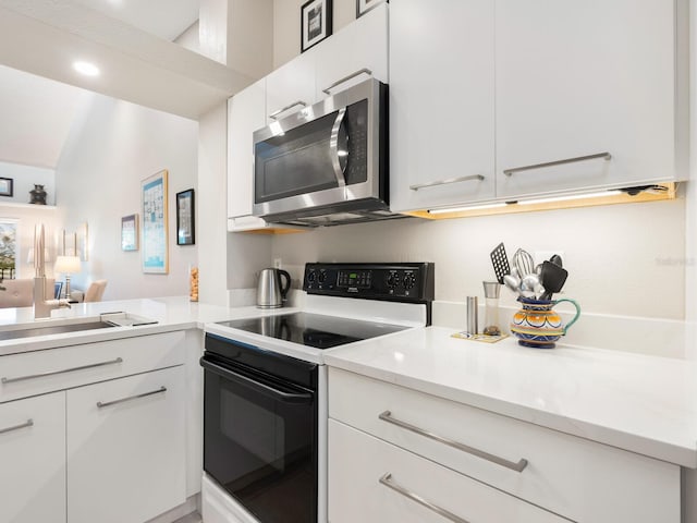 kitchen featuring white cabinets and white range with electric stovetop