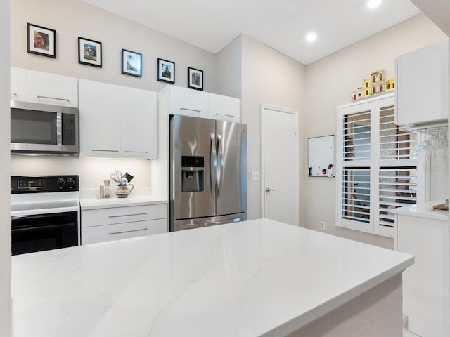 kitchen featuring appliances with stainless steel finishes, white cabinets, and light stone counters