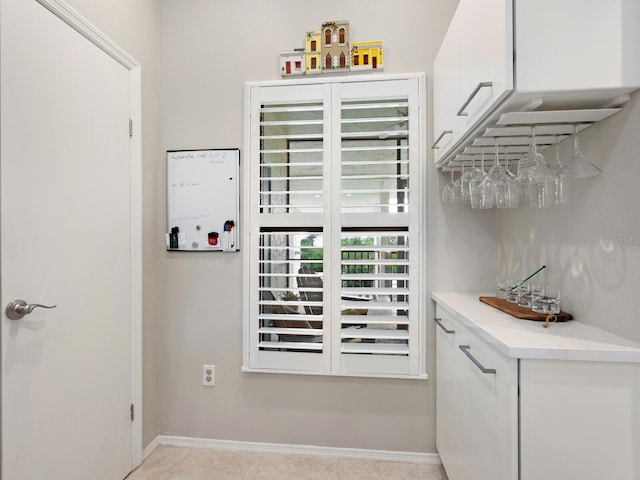 bar with light tile patterned floors and white cabinetry