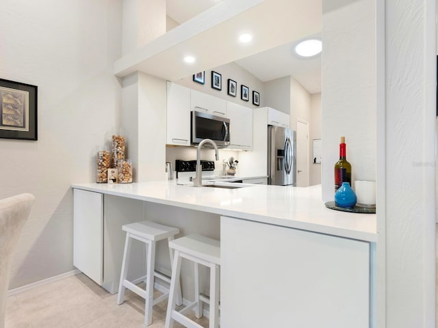 kitchen with kitchen peninsula, stainless steel appliances, white cabinetry, and light tile patterned floors