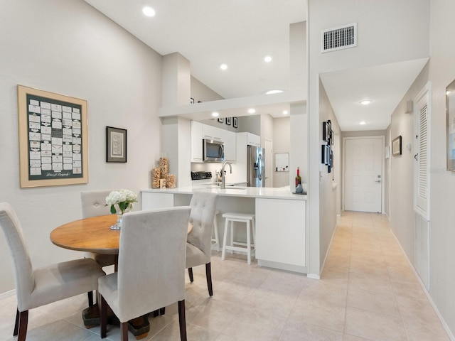 dining area with light tile patterned flooring, sink, and a high ceiling