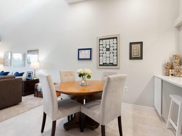 dining area featuring light tile patterned flooring and a towering ceiling