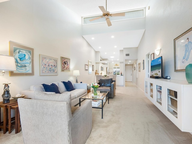 carpeted living room with ceiling fan and high vaulted ceiling