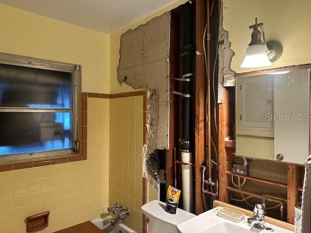 bathroom with tile walls, toilet, and sink