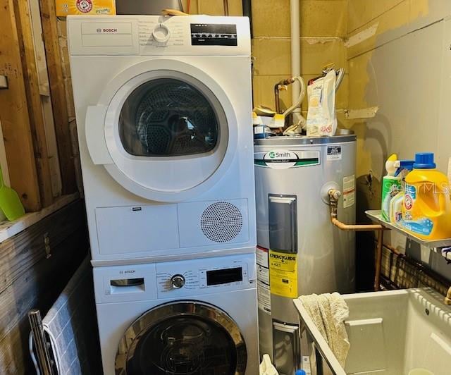 clothes washing area featuring stacked washer and clothes dryer and water heater